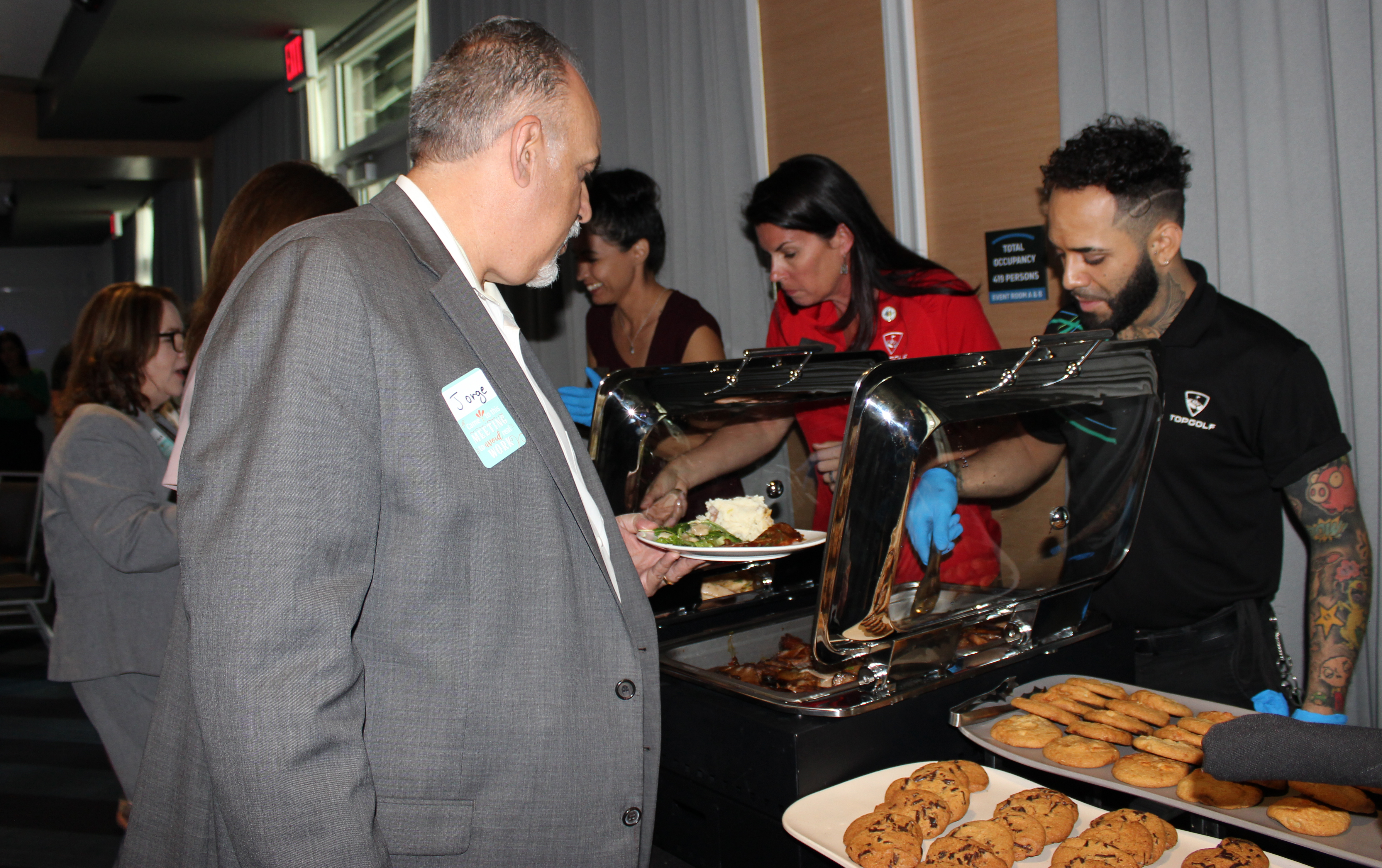 Doral Chamber of Commerce introduces members picking out food from the table at Topgolf Doral Networking Luncheon Event.